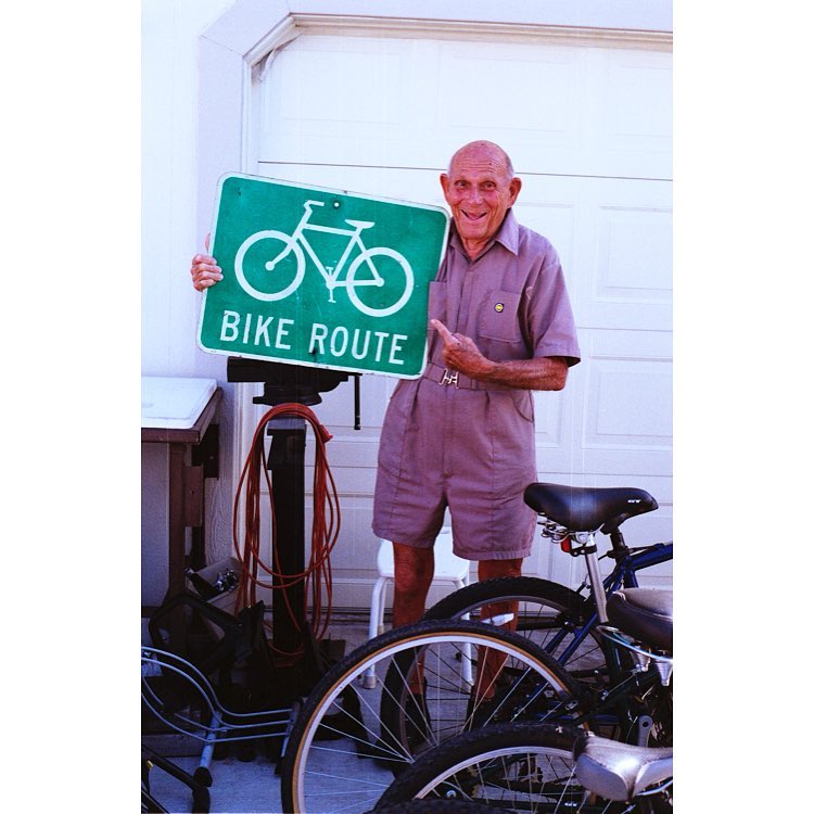 Old man holding bike route sign