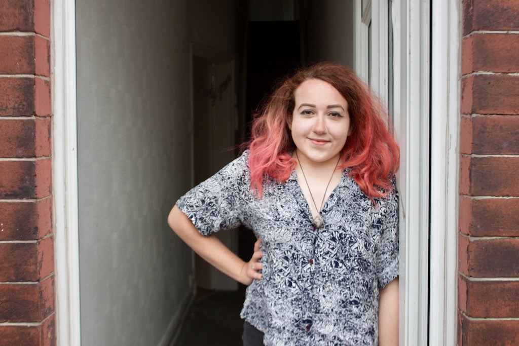 Person with orange hair posing at their front door